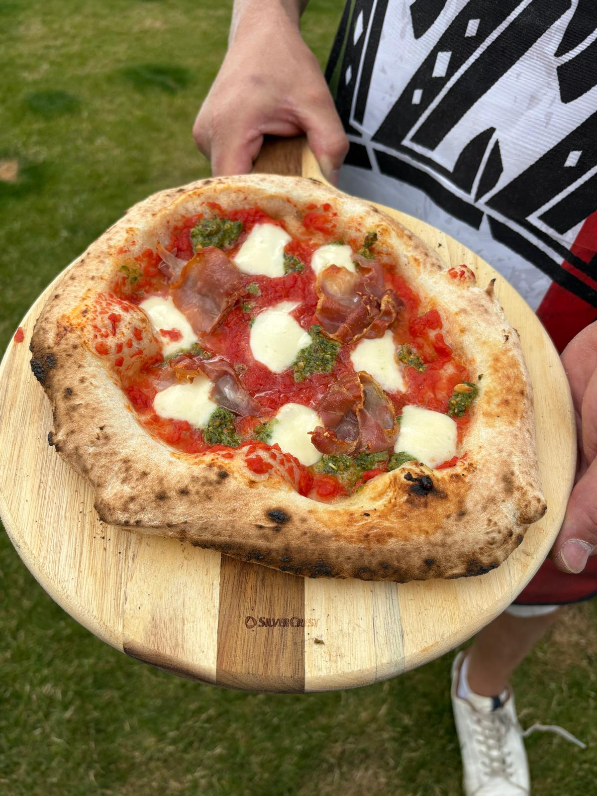 Vers gebakken pizza op de schep tijdens een sfeervol buitenfeest